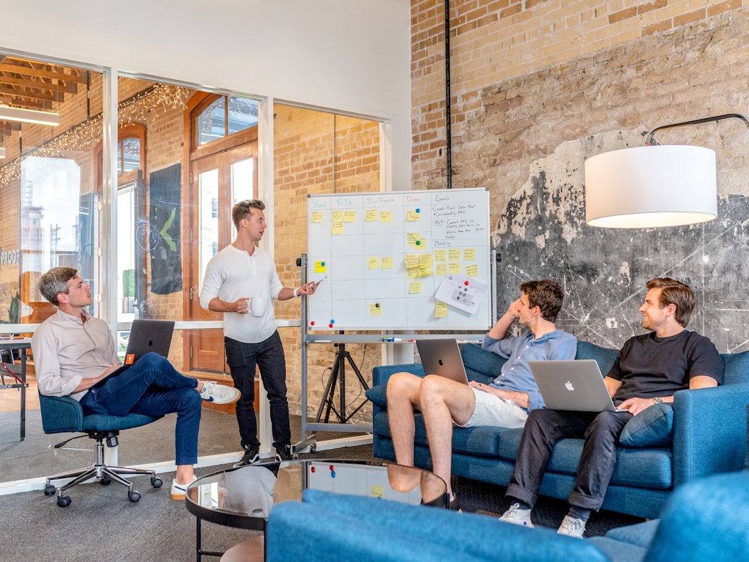 Sales manager coaching reps around a whiteboard during a team meeting