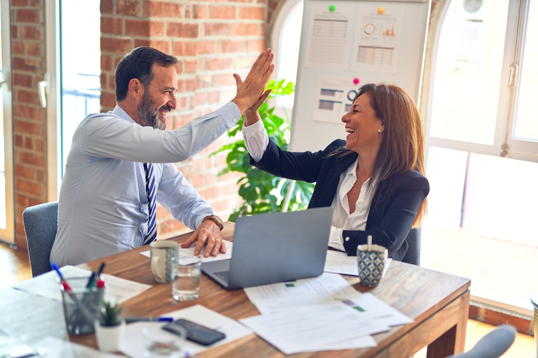 Two confident sales reps giving a high five after closing a deal