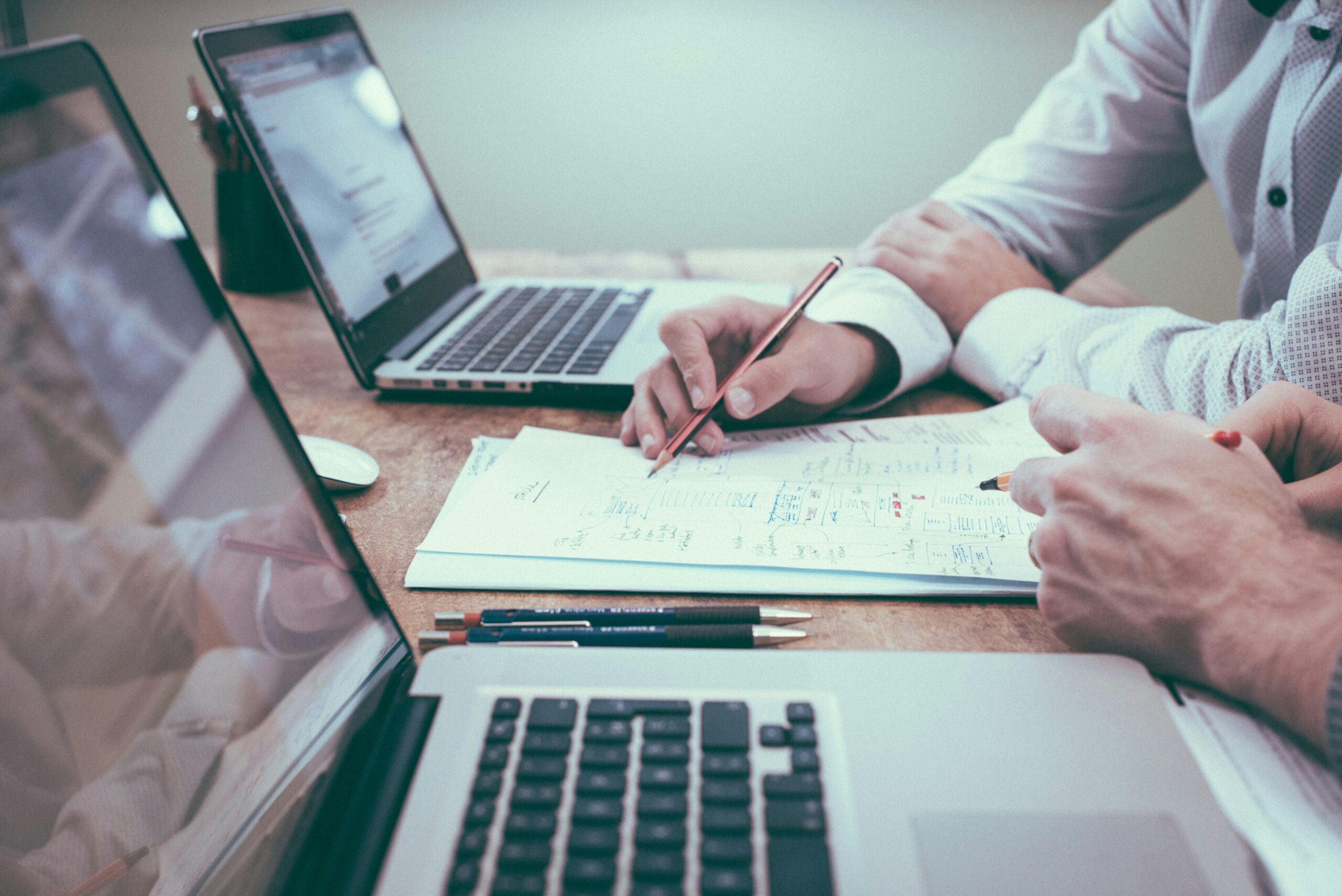 Two colleagues reviewing printed data and documents together at a table, representing an analytical buyer's evidence-first evaluation process